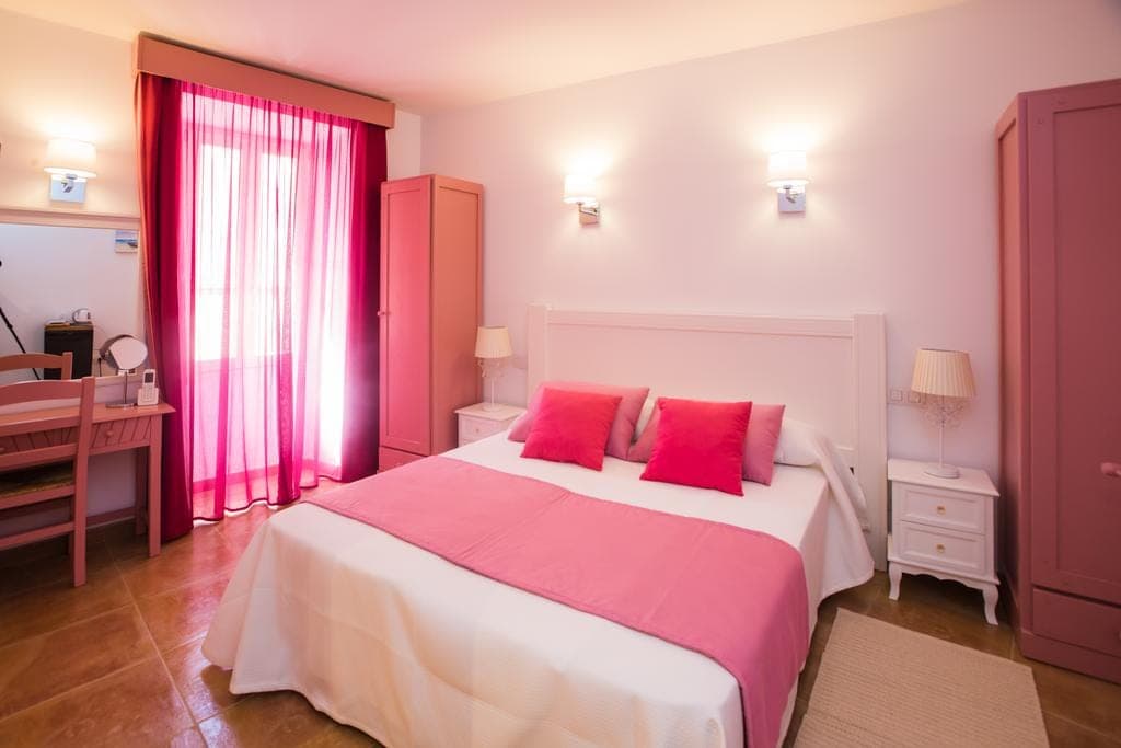 Zimmer im Boutique Hotel Can Serrete mit Doppelbett und farbigen Kissen