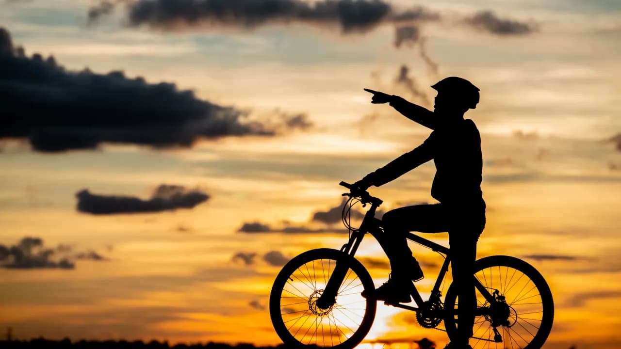 Self-guided cycling holidays in Mallorca: a cyclist pointing into the sunset