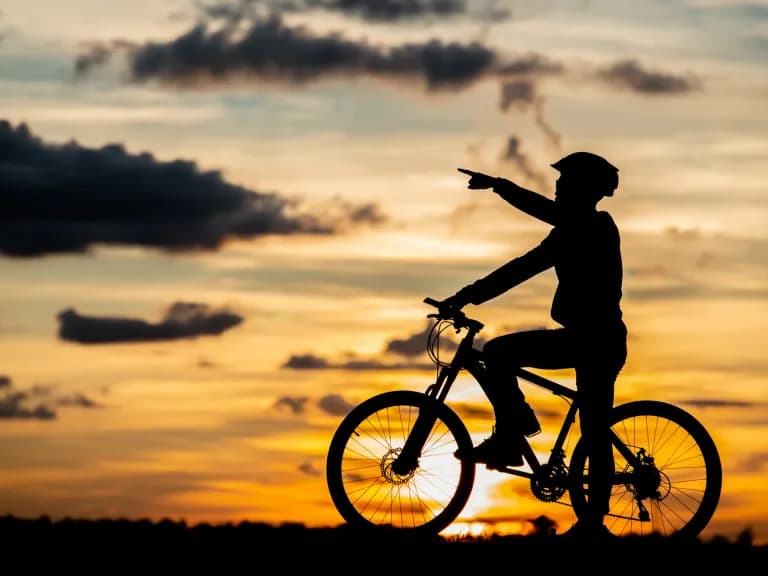 Self-guided cycling holidays in Mallorca: a cyclist pointing into the sunset