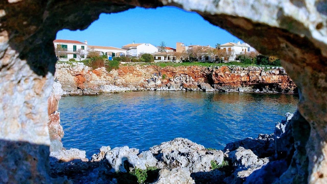 Blick durch einen Felsbogen auf die Küste bei Porto Cristo